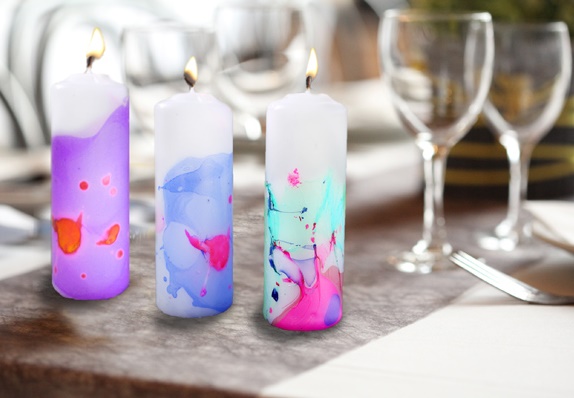3 candles decorated with coloured nail poish on a table