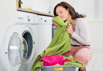Woman smelling fresh laundry from the washing machine
