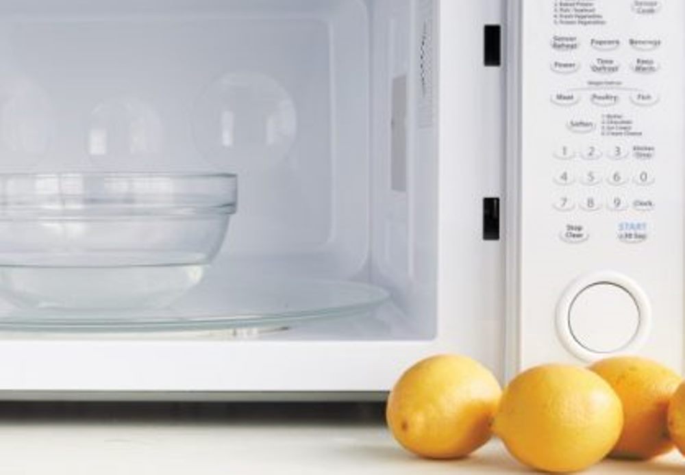 Lemon and bowl of water close to a microwave